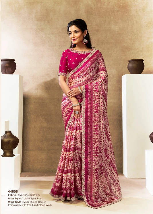 Woman wearing a pink saree with traditional patterns in an indoor setting.