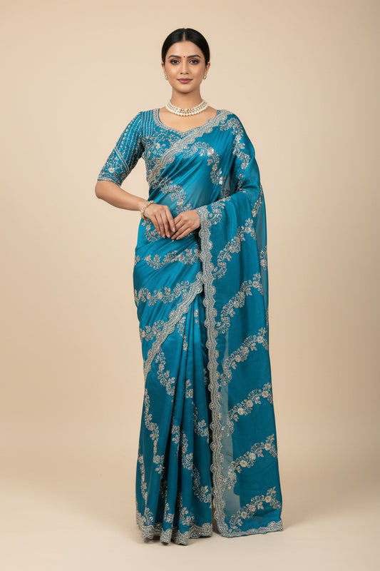 Blue saree with white embroidery on a mannequin in a room with a sofa and plant.