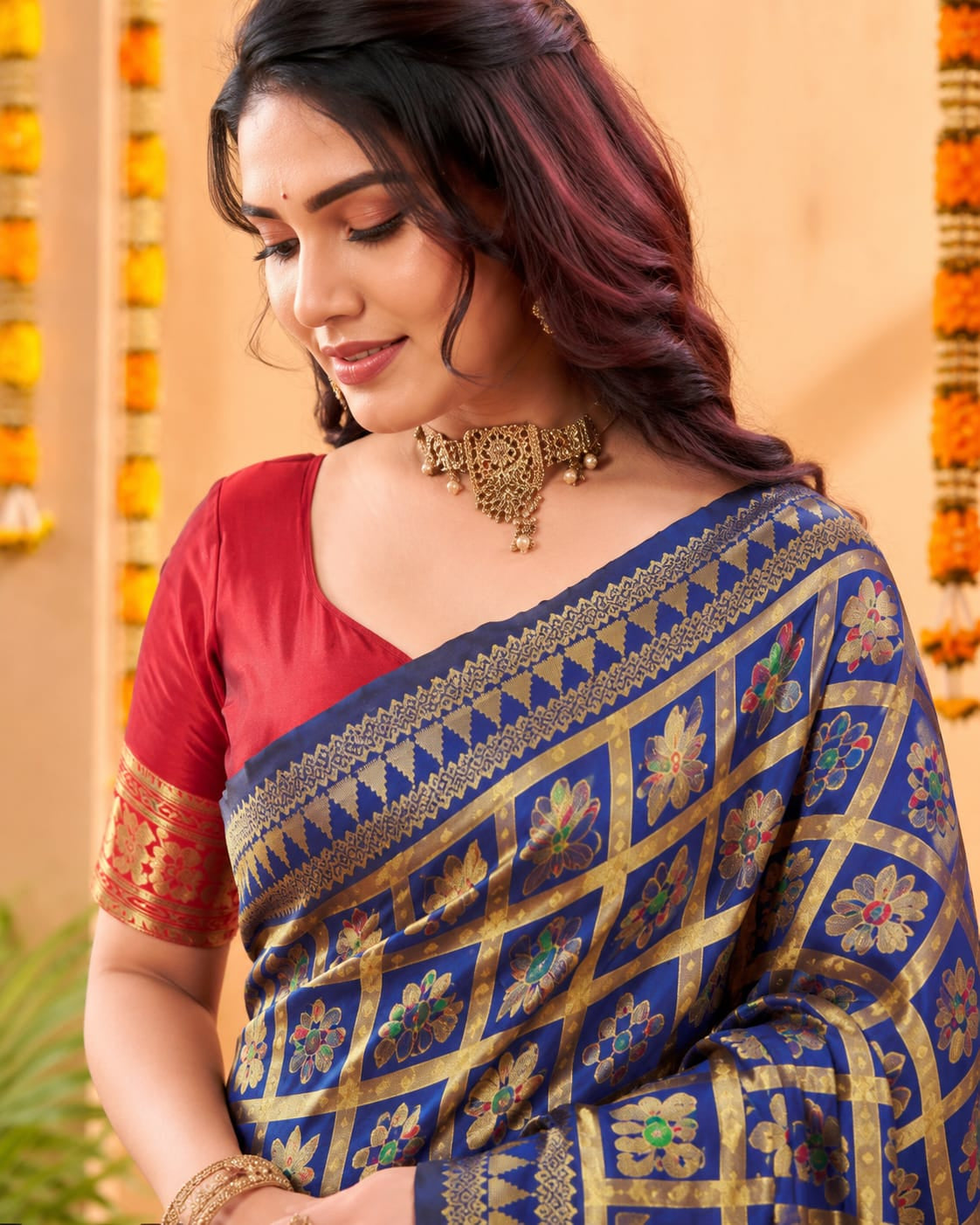 Close-up of royal blue jacquard saree with gold-tone checks and colourful floral motifs