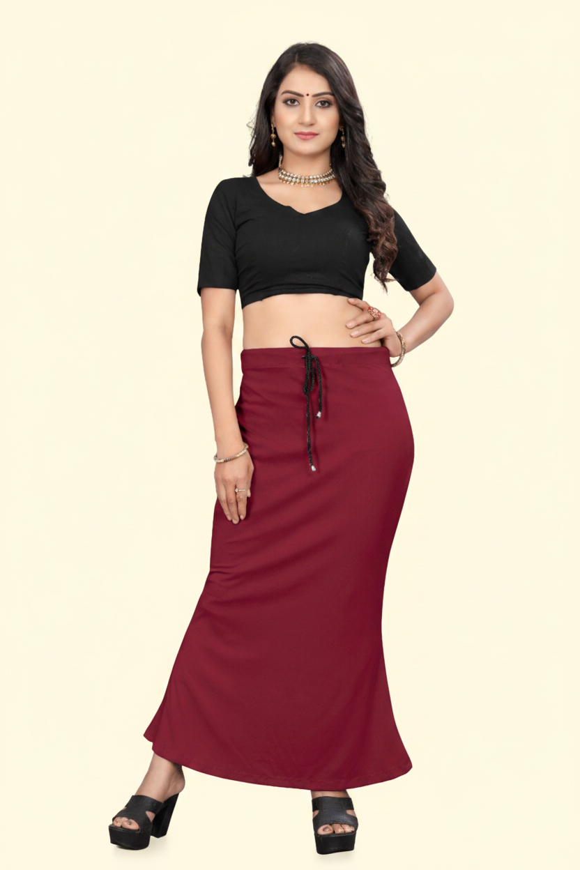 Woman wearing a black top and maroon skirt on a beige background
