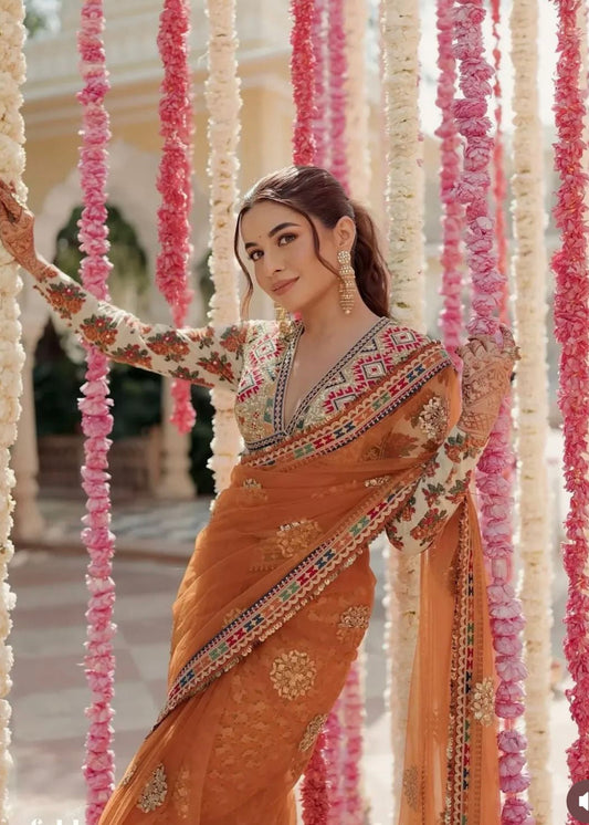 Woman in an ornate orange saree standing among floral decorations