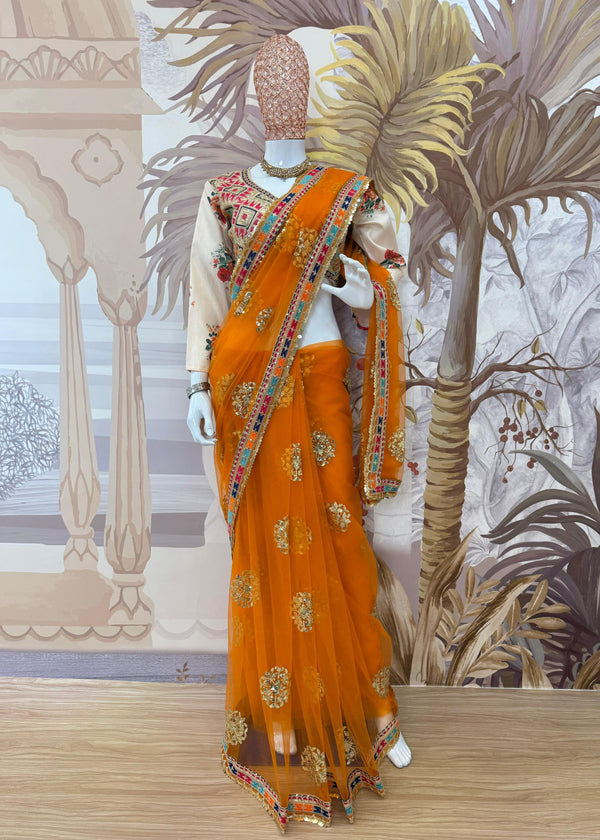 Orange saree with gold patterns on a mannequin against a decorative background