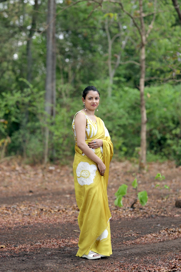 Woman in a yellow saree standing in a forested area