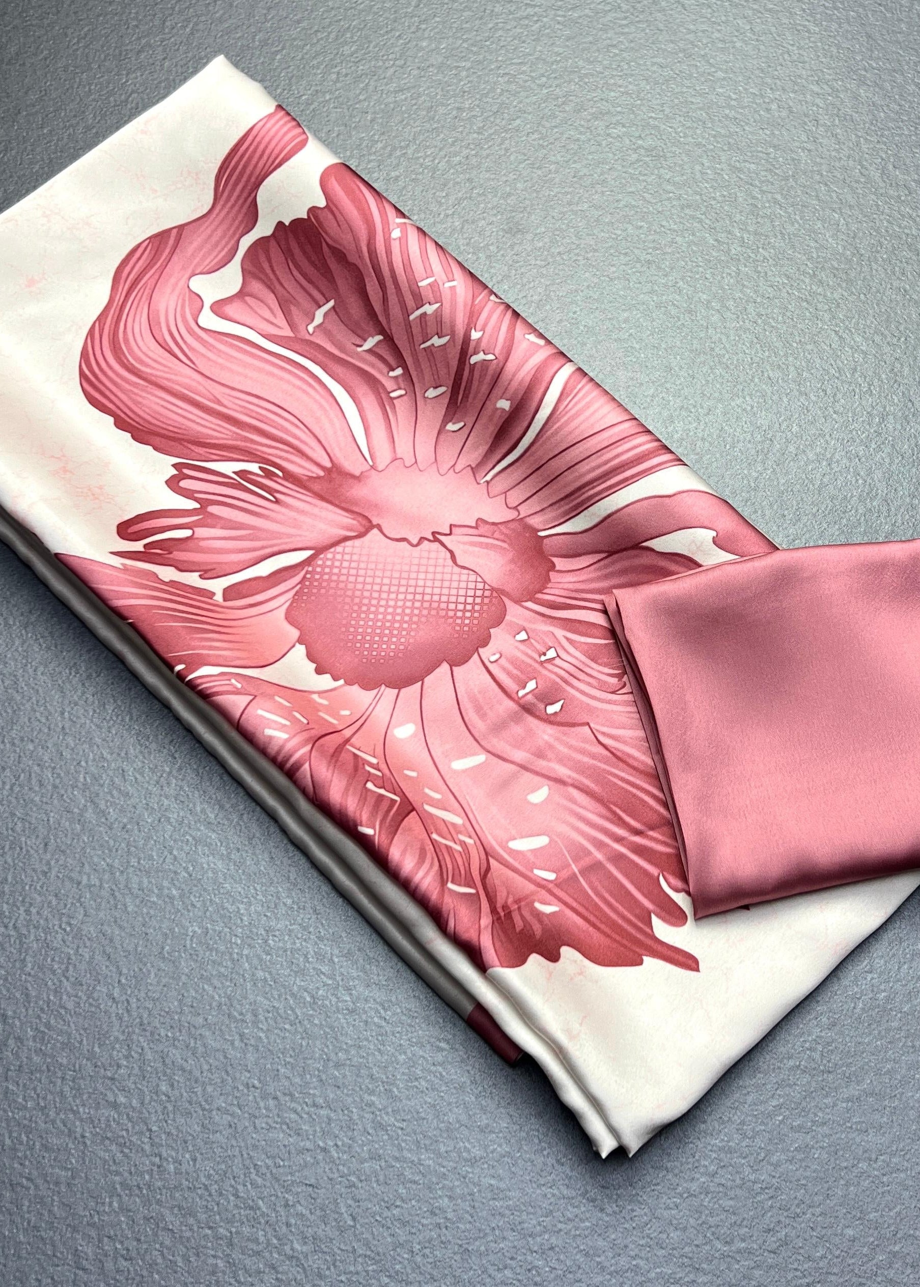 Pink floral scarf and pouch on a gray surface