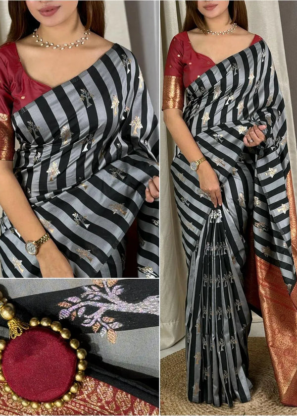 Woman wearing a black and white striped saree with gold accents, holding a matching blouse and a decorative bag.