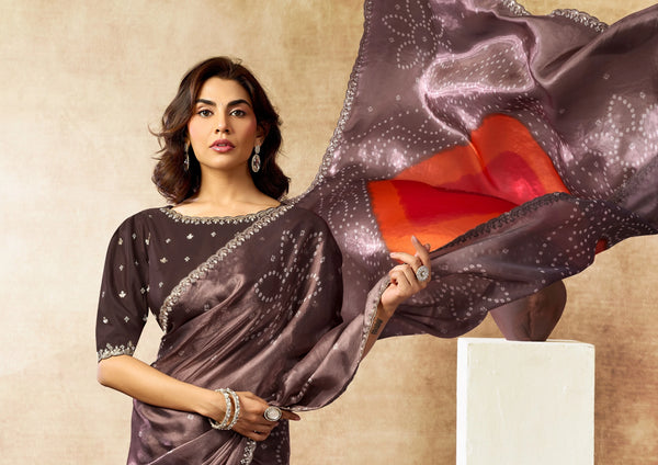Woman wearing a traditional saree with a red blouse against a beige background