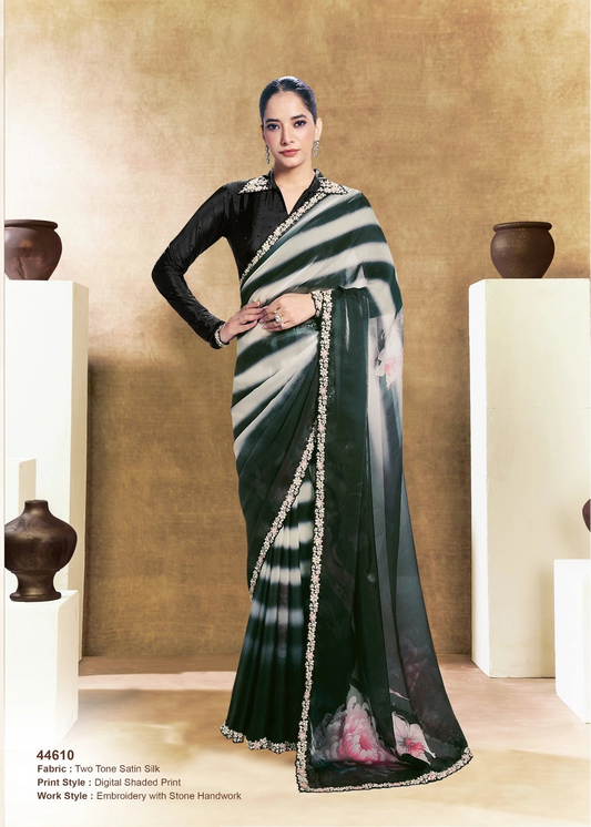 Woman wearing a black and white saree with a gold border, posing indoors.