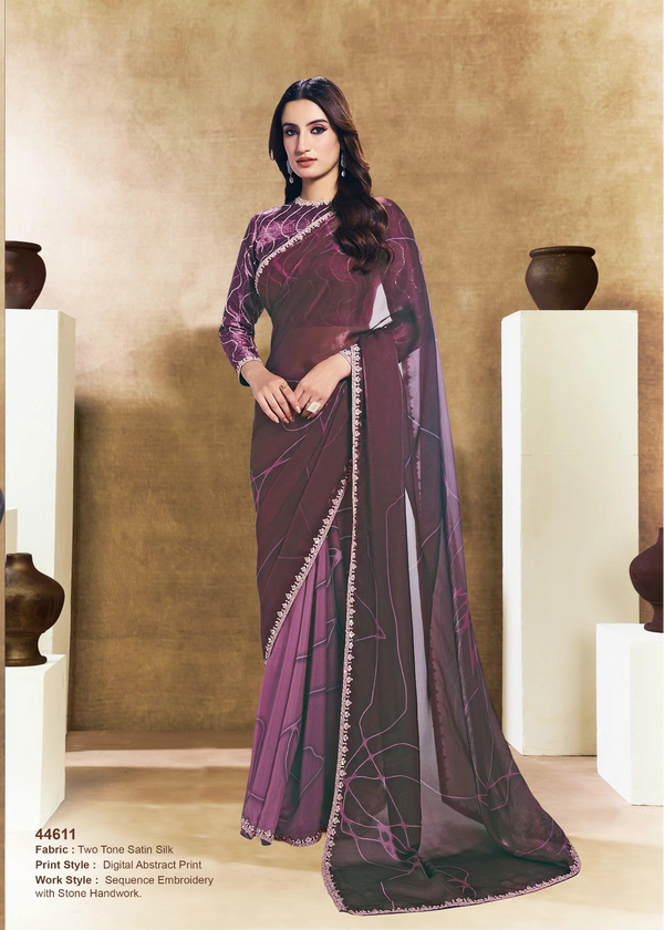 Woman wearing a purple saree with a gold border in an indoor setting.
