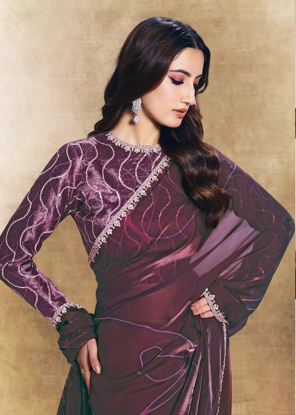 Woman wearing a purple saree with a gold border in an indoor setting.