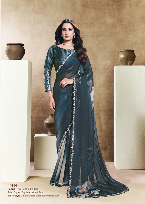 Woman wearing a dark green saree with silver border in an indoor setting.