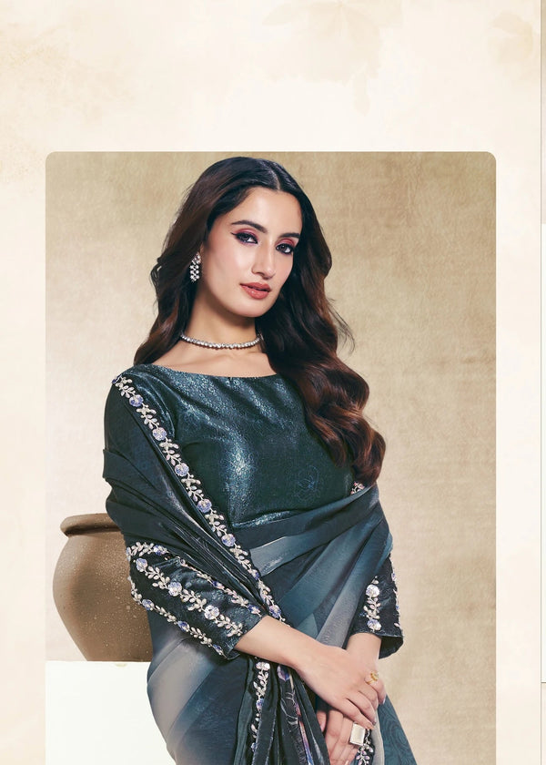 Woman wearing a dark green saree with silver border in an indoor setting.