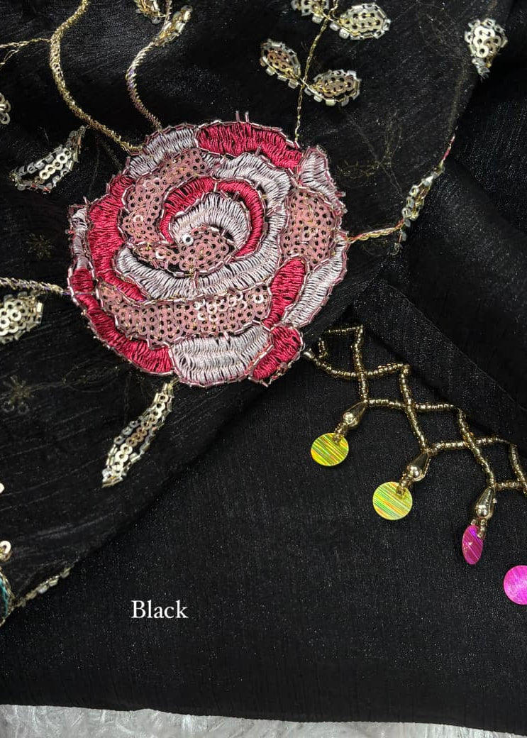Close-up of black fabric with pink embroidered rose and decorative elements.