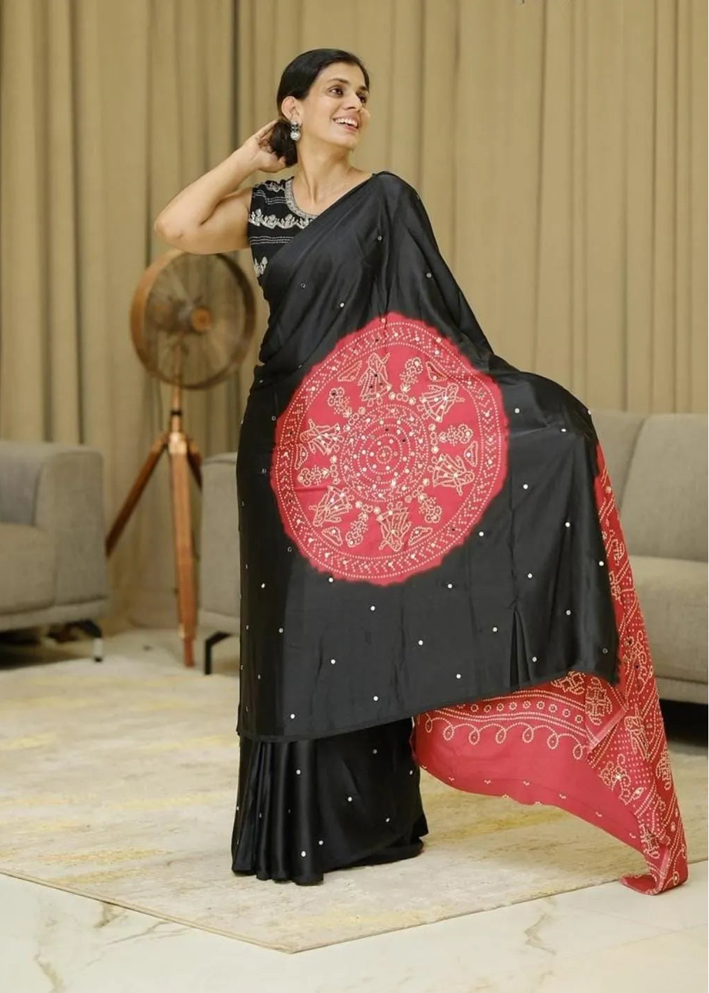 Woman wearing a black saree with red and white patterns in an indoor setting
