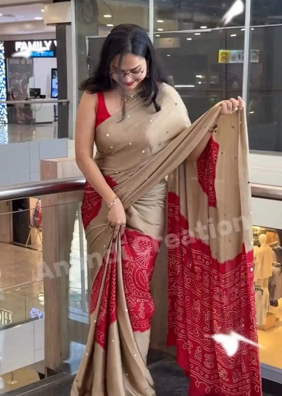 Woman holding a red and beige saree in an indoor setting