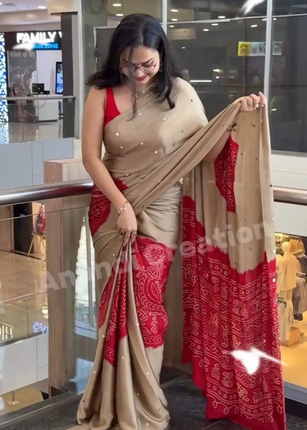 Woman holding a red and beige saree in an indoor setting