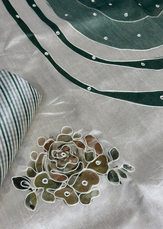 Embroidered flower design on fabric with a striped pillow in the corner