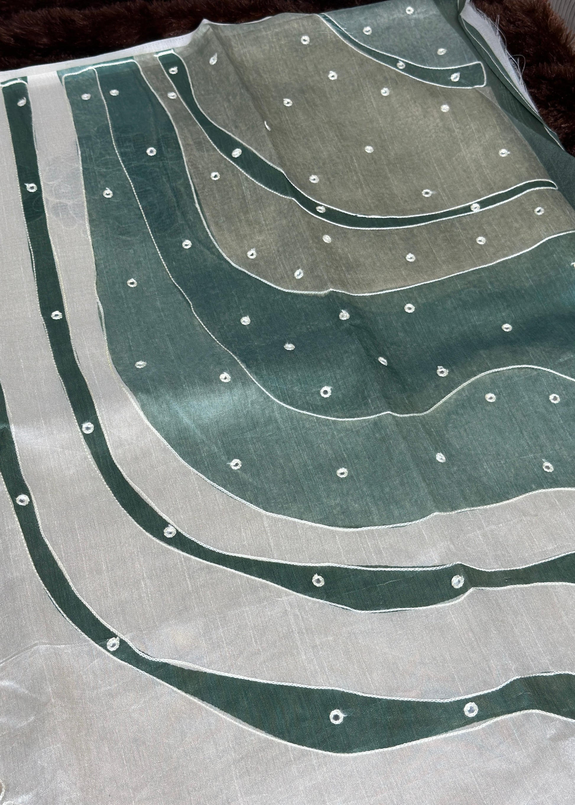 Textile with green and gray pattern and small white dots on a plain background
