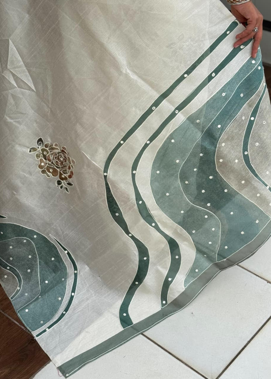 Embroidered fabric with green and white patterns on a tiled floor