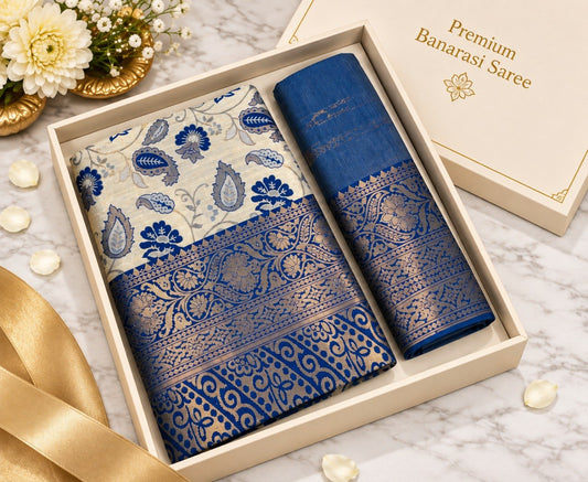 Blue Banarasi silk saree with ivory floral motifs and heavy gold zari blue border, shown in a gift box with the matching blue unstitched blouse piece