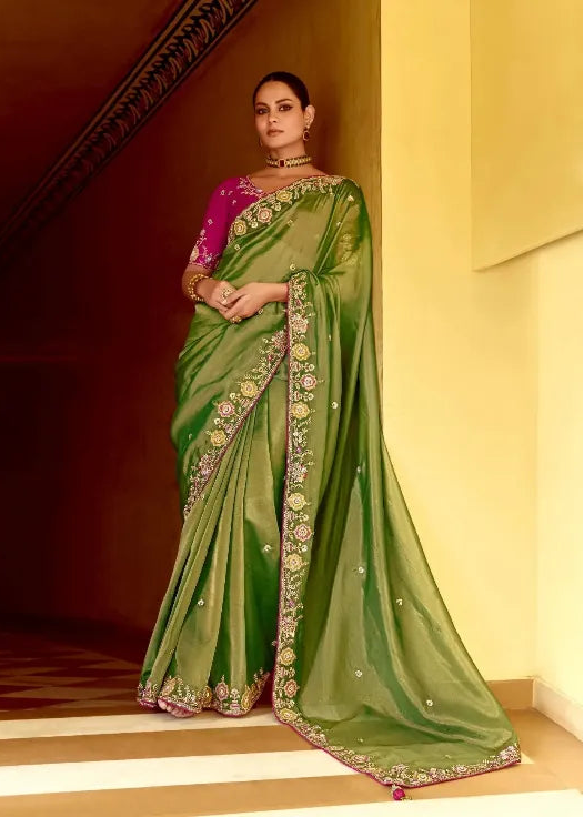 Woman wearing a green saree with pink blouse in an indoor setting