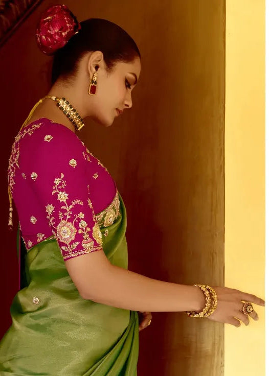 Woman in a pink blouse and green saree looking into a mirror.