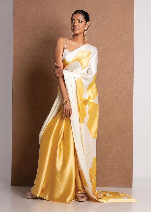 Woman wearing a yellow and white saree against a brown background