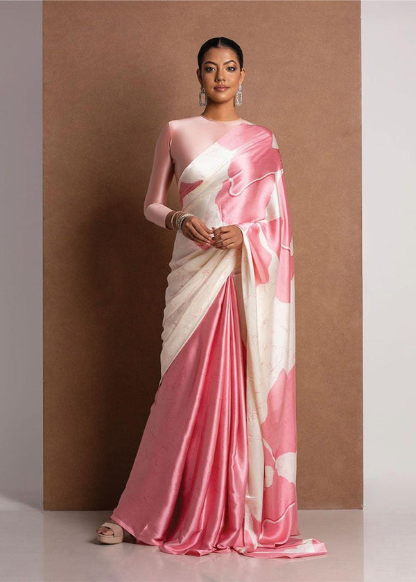 Woman wearing a pink and white saree against a brown background