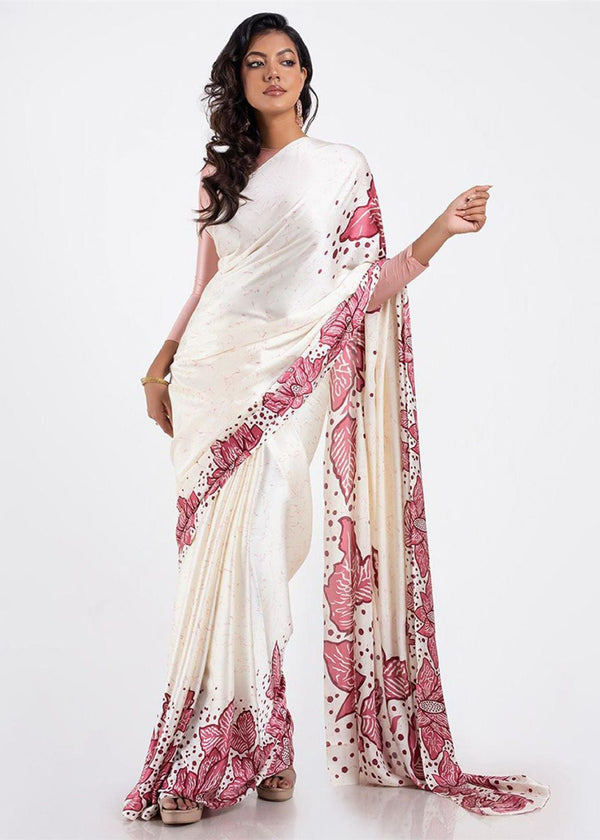 Woman wearing a white saree with pink floral patterns on a white background