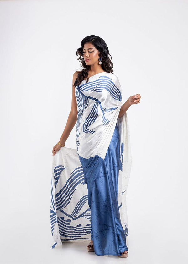 Woman wearing a white and blue patterned saree on a white background