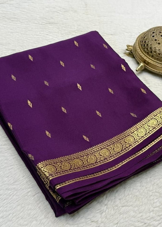 Purple fabric with gold border and patterns on a textured white surface