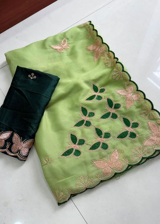 Green saree with floral patterns and black blouse on a white surface