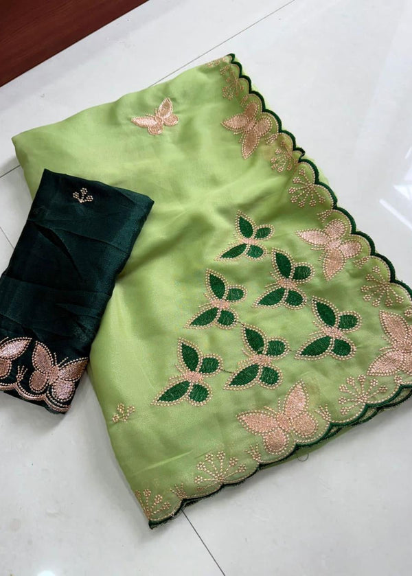 Green saree with floral patterns and black blouse on a white surface